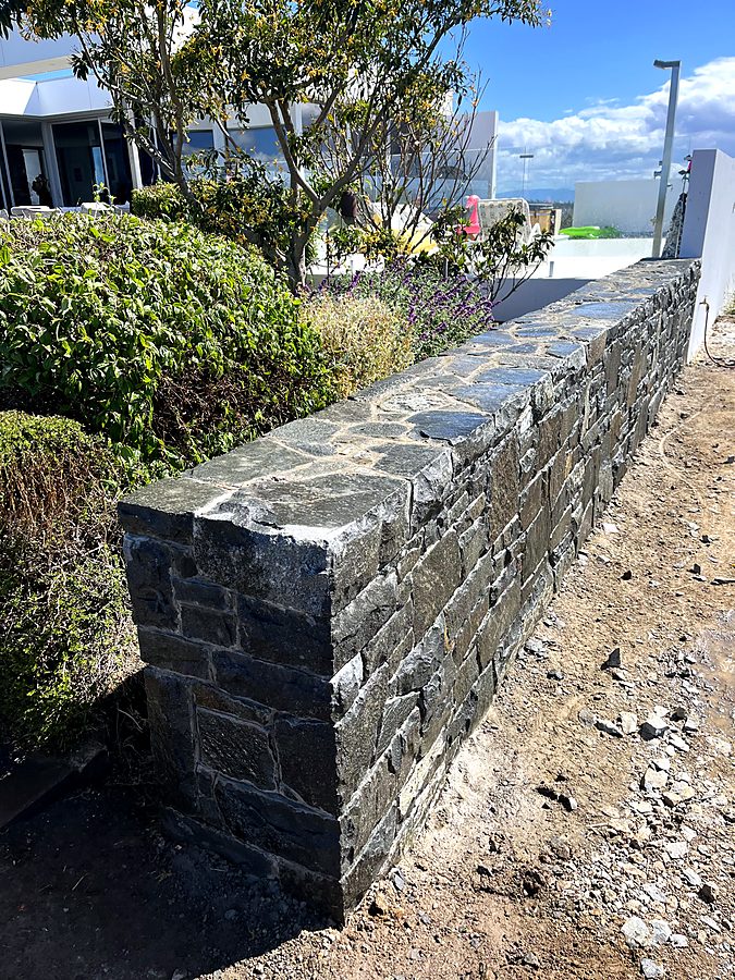 Bluestone wall with dressed stone capping beside a garden bed