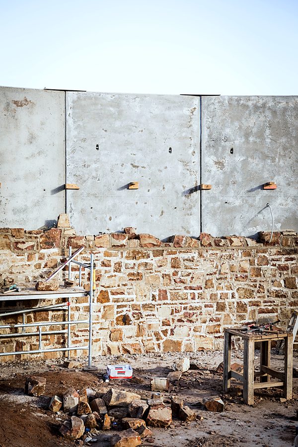 Heritage rubble wall part-rebuilt beneath new concrete panels