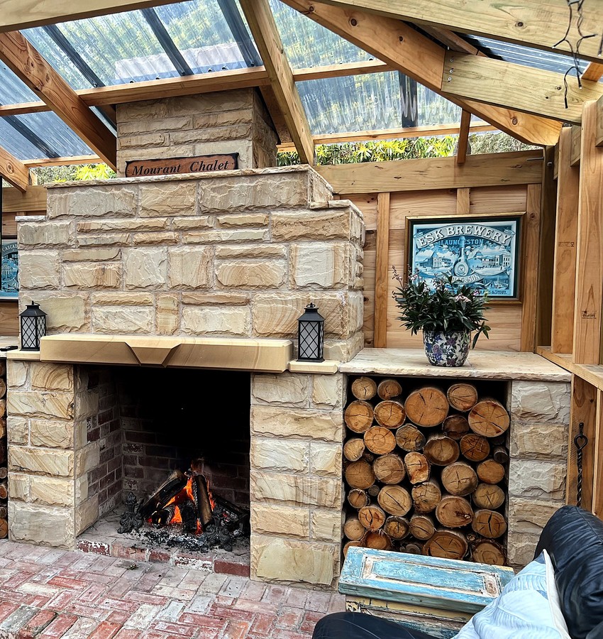 Outdoor sandstone fireplace with a fire burning