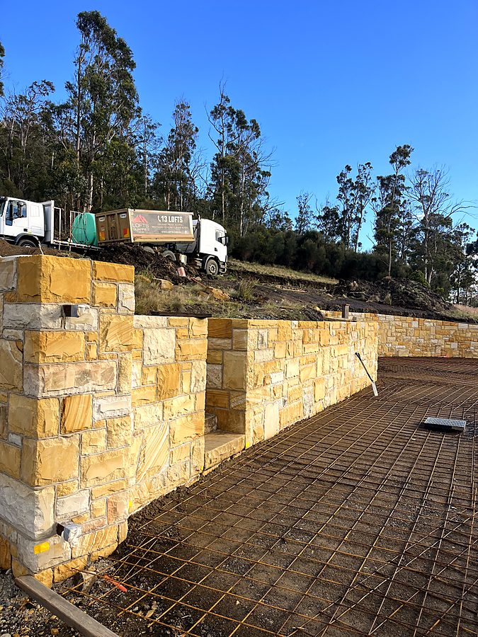 Dressed sandstone retaining wall and pillars in low afternoon light