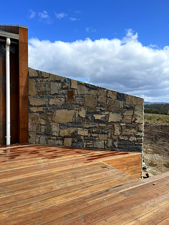 Raking stone feature wall against corten steel cladding