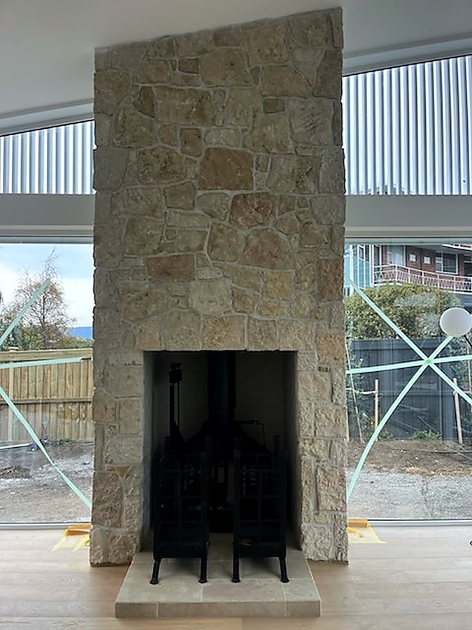 Full-height stone chimney breast with freestanding wood heater