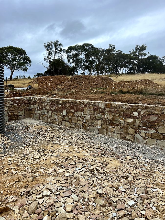 Curved stone retaining wall beside a water tank