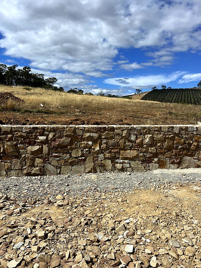 Long stone retaining wall with dressed capping