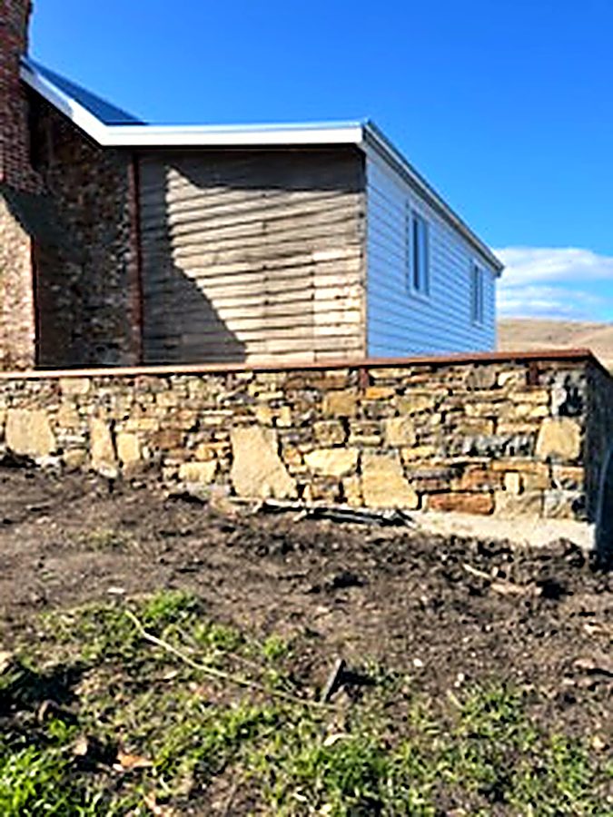 Stone wall running beside a timber-clad building