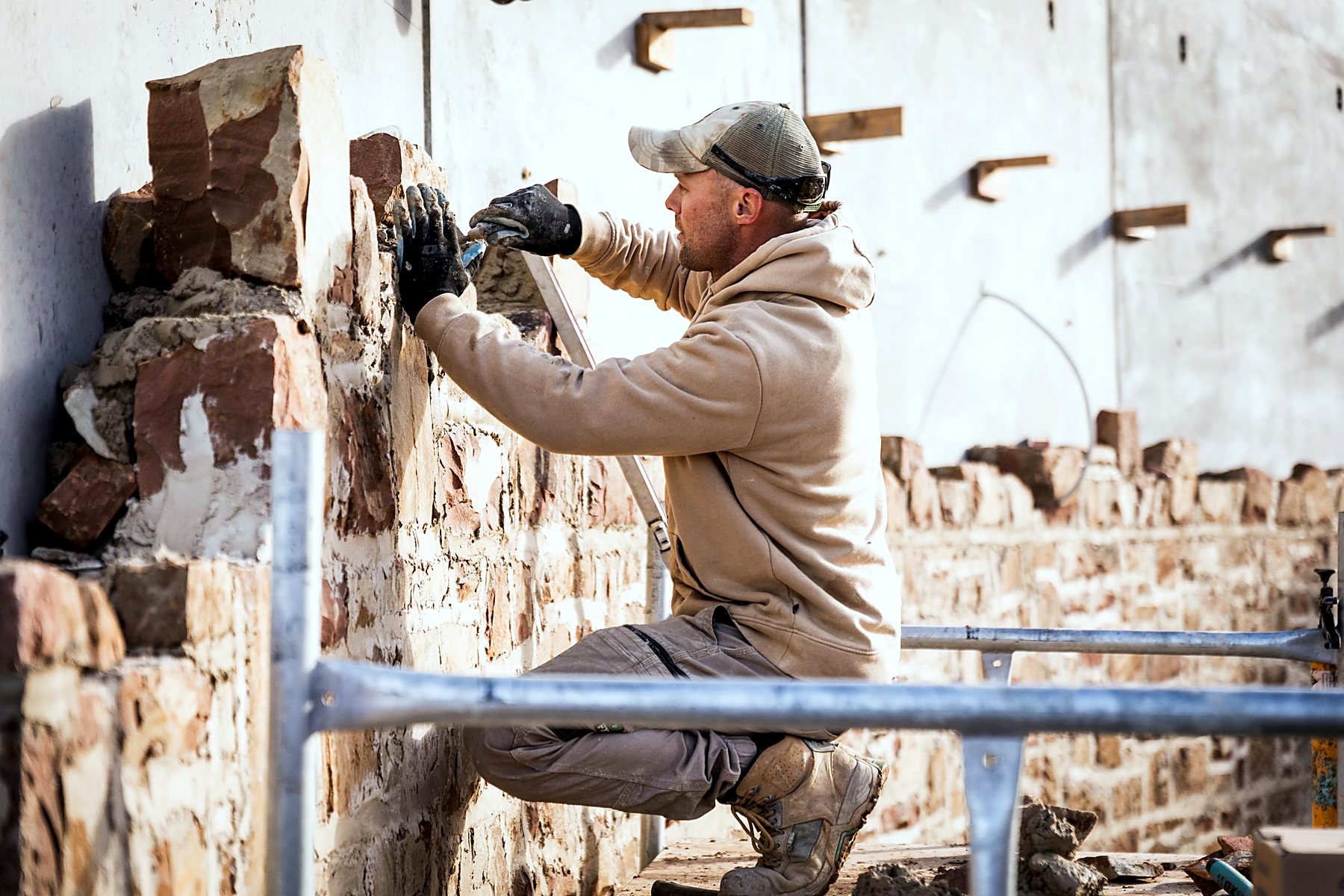 Stonemason working mortar into a heritage sandstone wall by hand